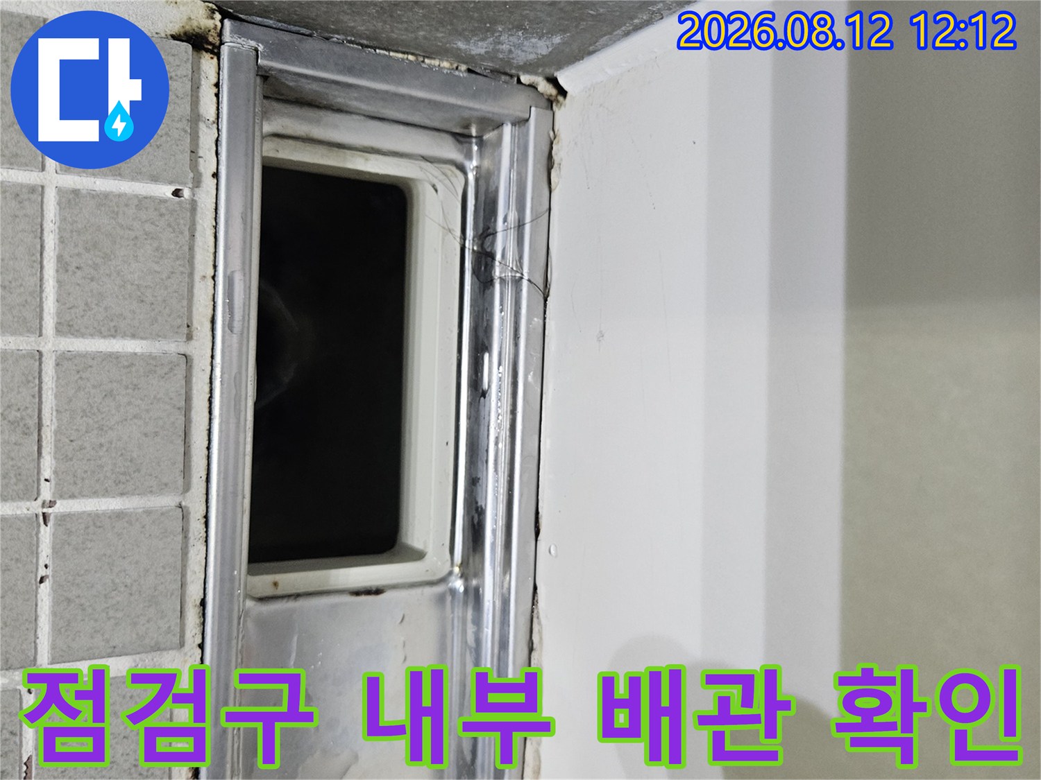 화장실 천장 점검구를 통해 본 배관 트레이와 주변 마감재 모습입니다.