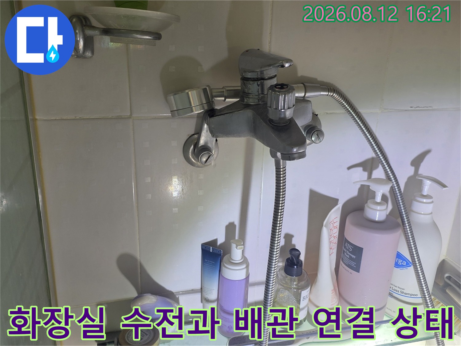 은색 금속 재질의 욕실 수도꼭지와 샤워 호스가 연결된 벽면 모습