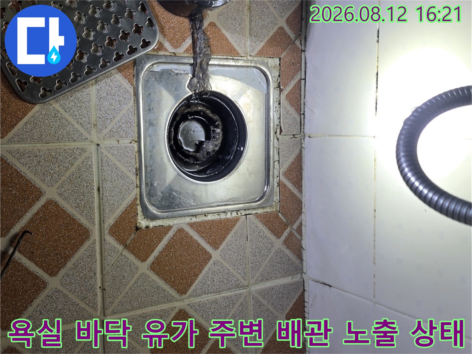 화장실 바닥의 금속제 배수구 유가와 연결된 검은색 플라스틱 배관-누수 점검을 위해 분리된 모습