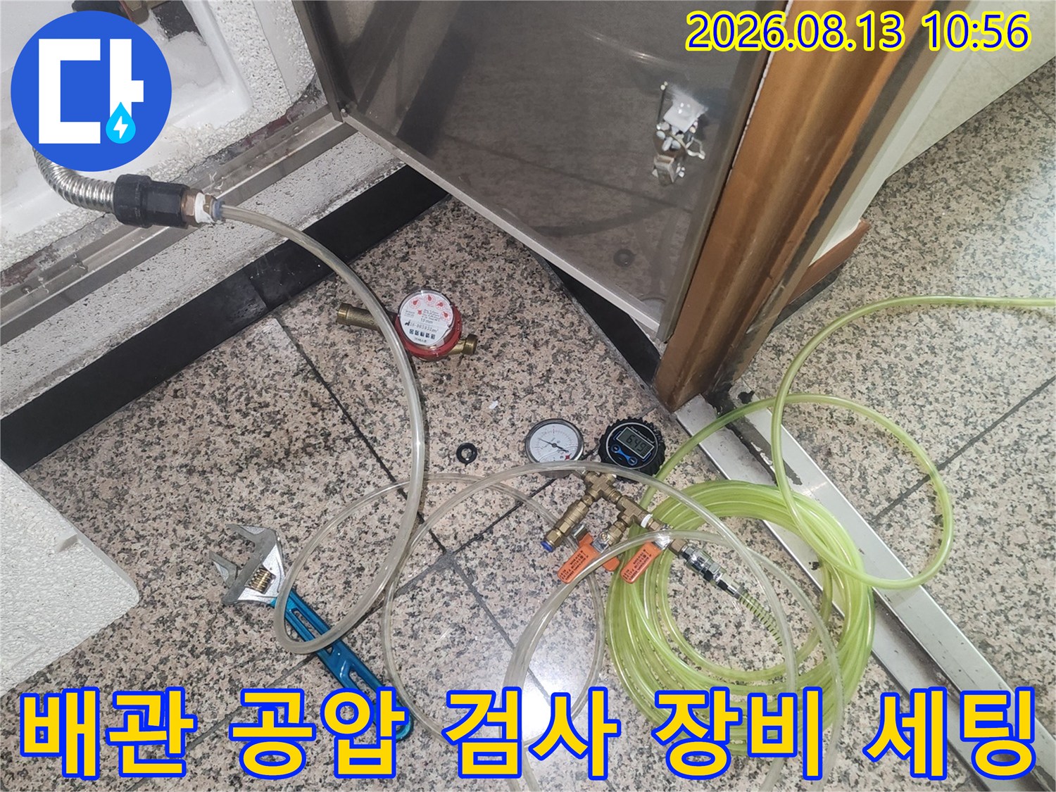 바닥 점검구 근처에 배치된 누수 탐지용 공압 테스트 호스와 압력계-장비들
