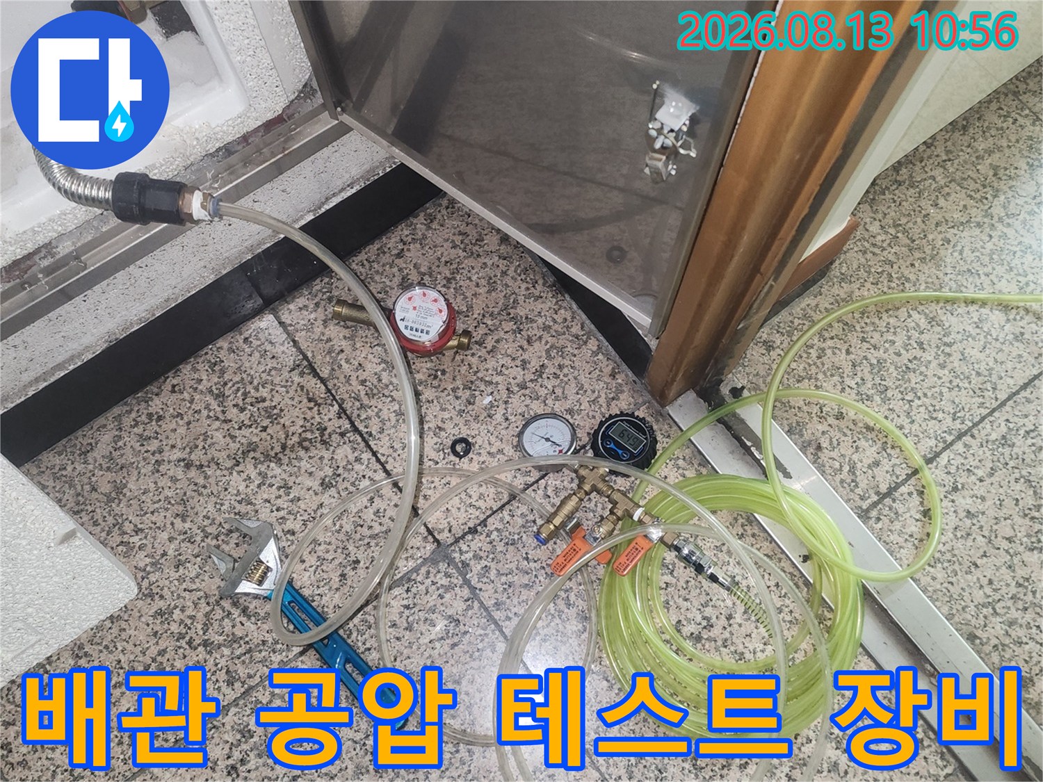 바닥 점검구 주변에 배치된 누수 탐지용 압력계와 호스-장비들