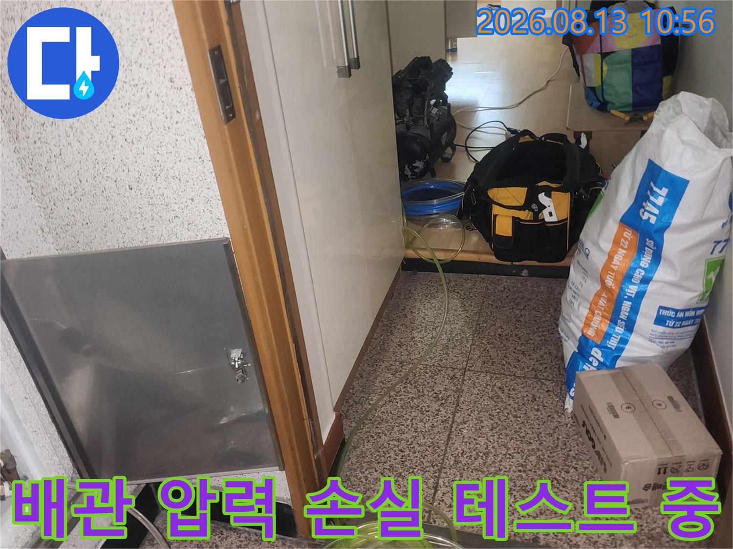 바닥 점검구를 통해 배관에 연결된 노란색 호스와 공압 측정 장치 모습