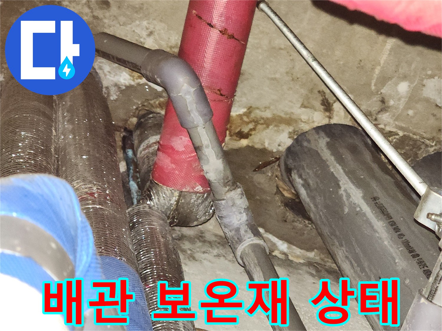 천장 내부의 붉은색 보임 배관과 금속 재질 관의 근접 촬영