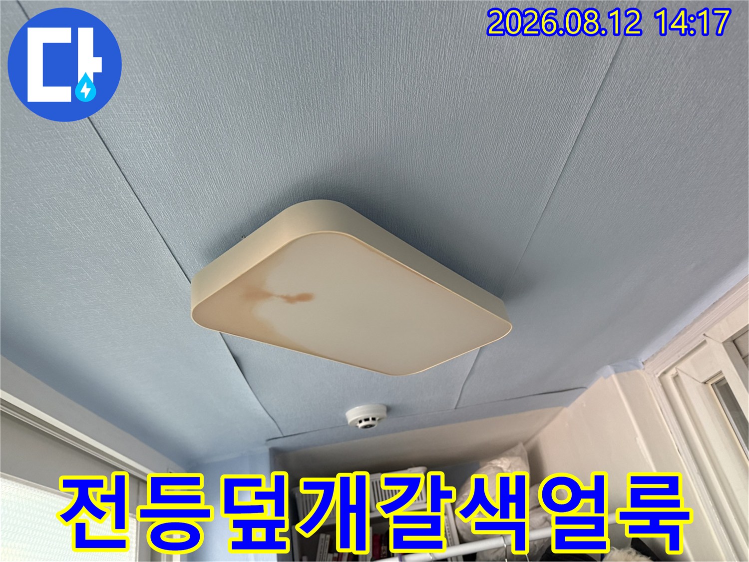 베란다의 푸른 천장에 설치된 조명 갓에 갈색 누수 얼룩이 있는 모습