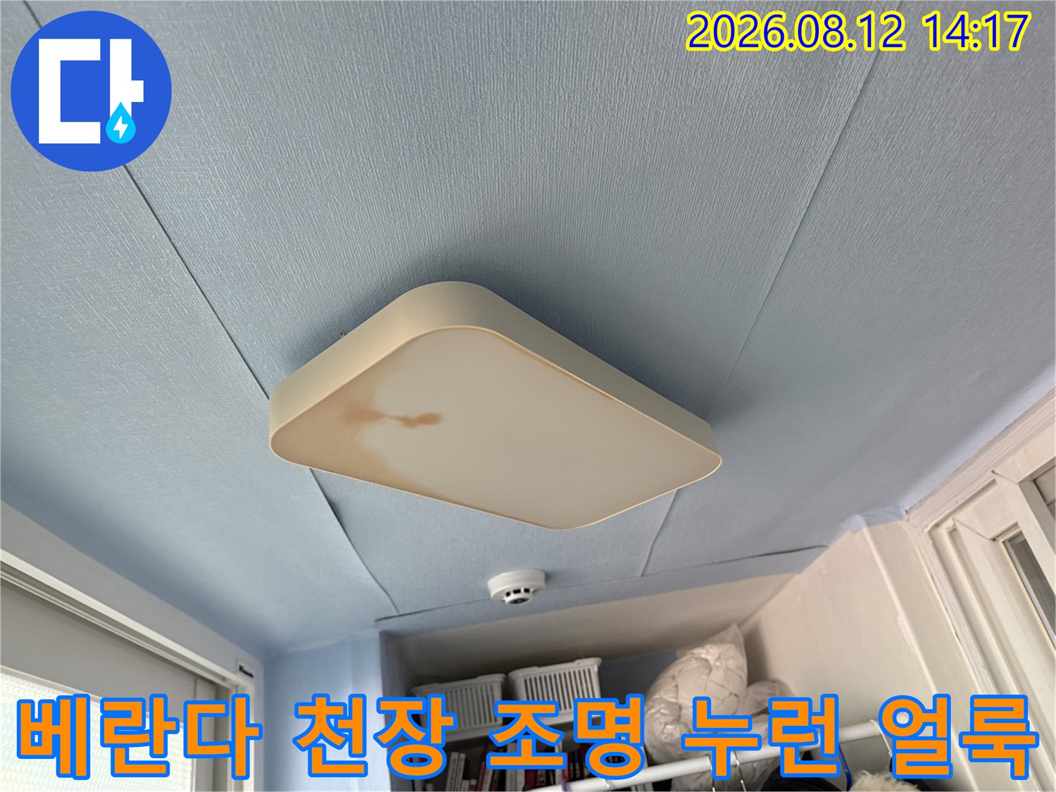 하늘색 베란다 천장과 사각형 전등 덮개 왼쪽에 형성된 갈색의 물 흐름 자국