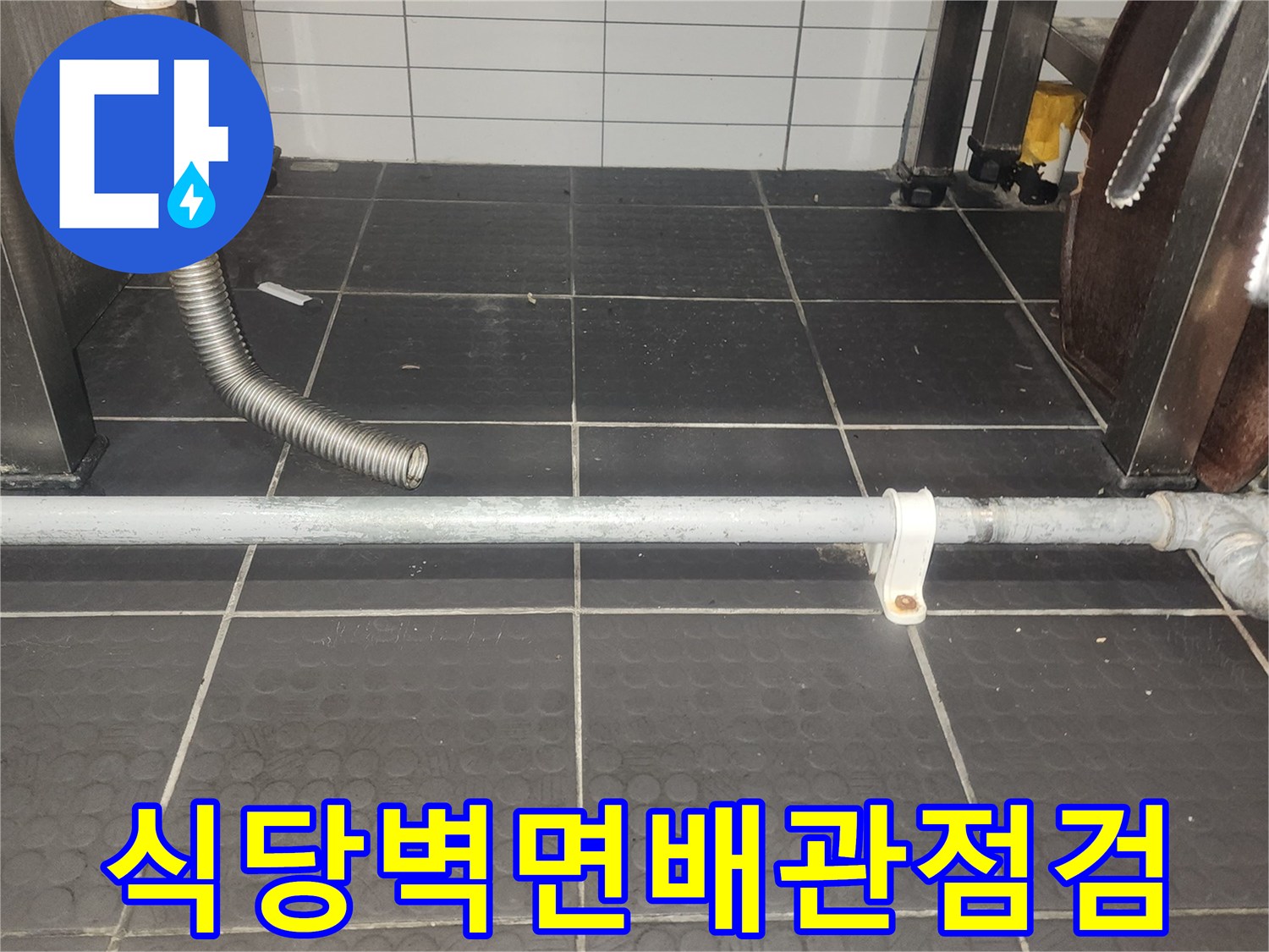 어두운 색상의 타일 벽면에 설치된 금속 배관과 호스 연결부
