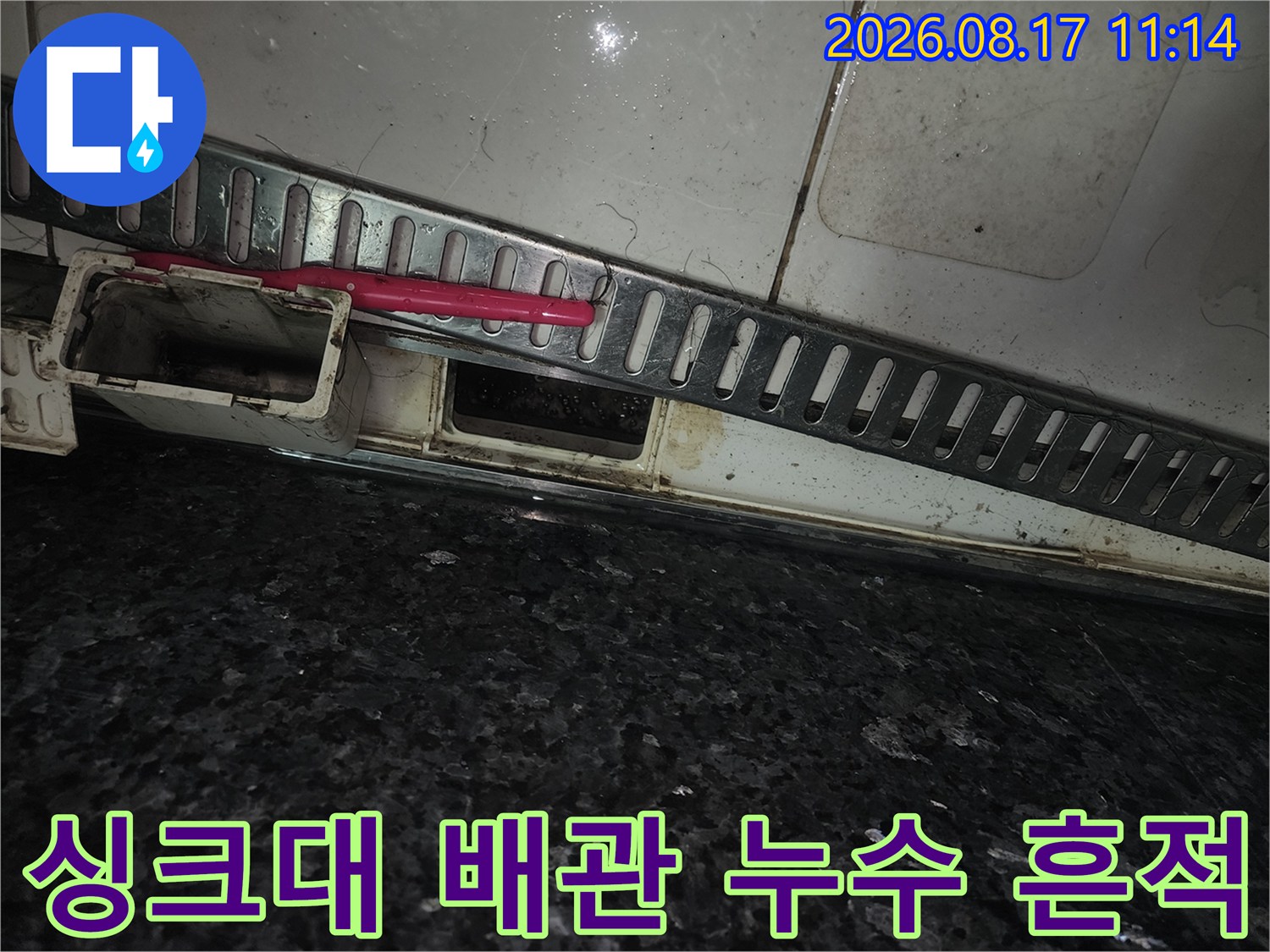 싱크대 하부장 아래쪽의 젖은 마감재와 오염된 배수구 부위를 촬영했습니다.