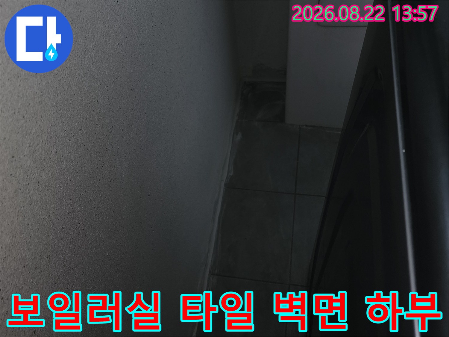 어두운 보일러실 구석의 타일 벽면과 바닥 경계 부위 사진입니다.