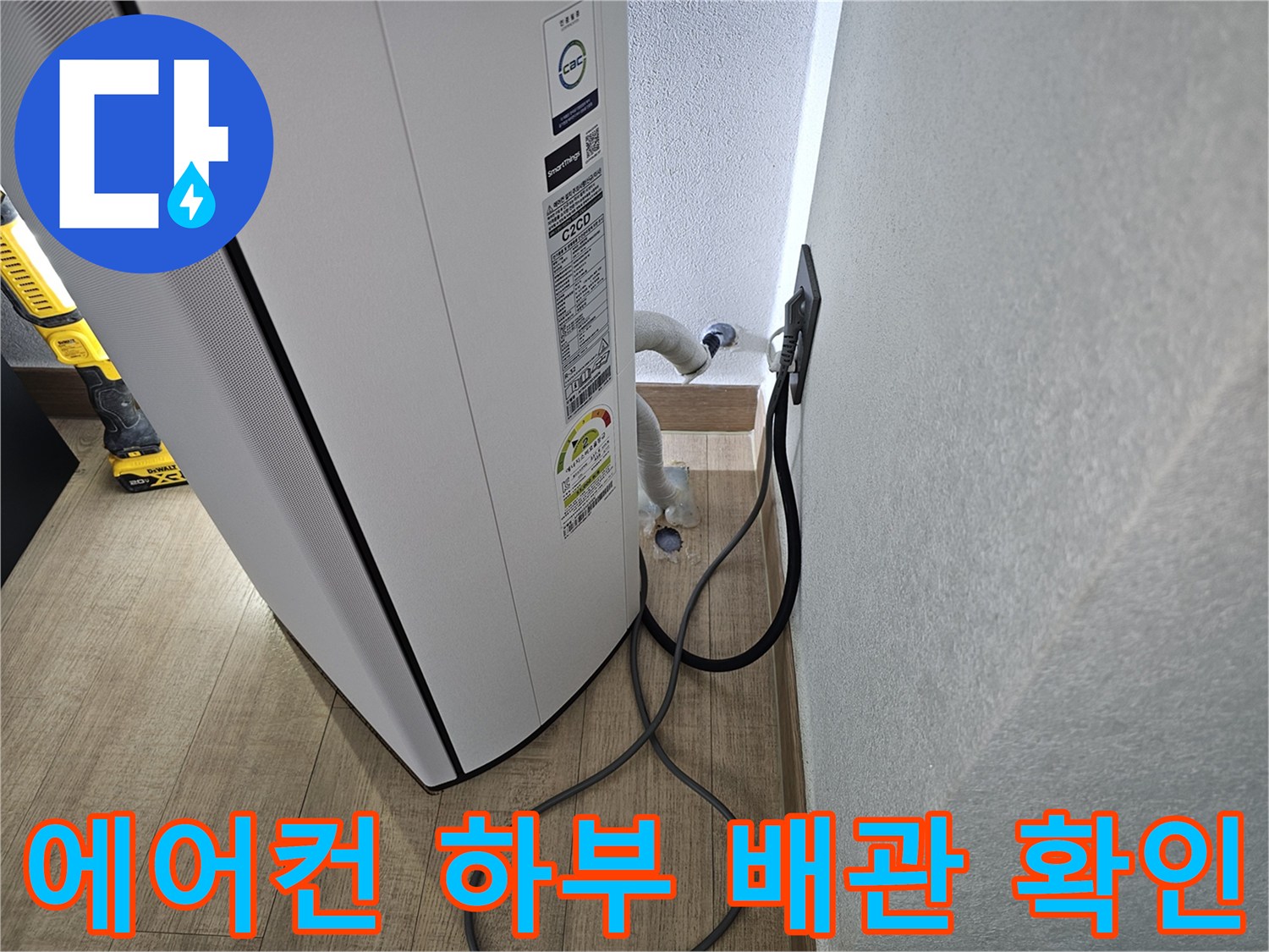 벽면 콘센트와 연결된 에어컨 배수 라인 근접 촬영