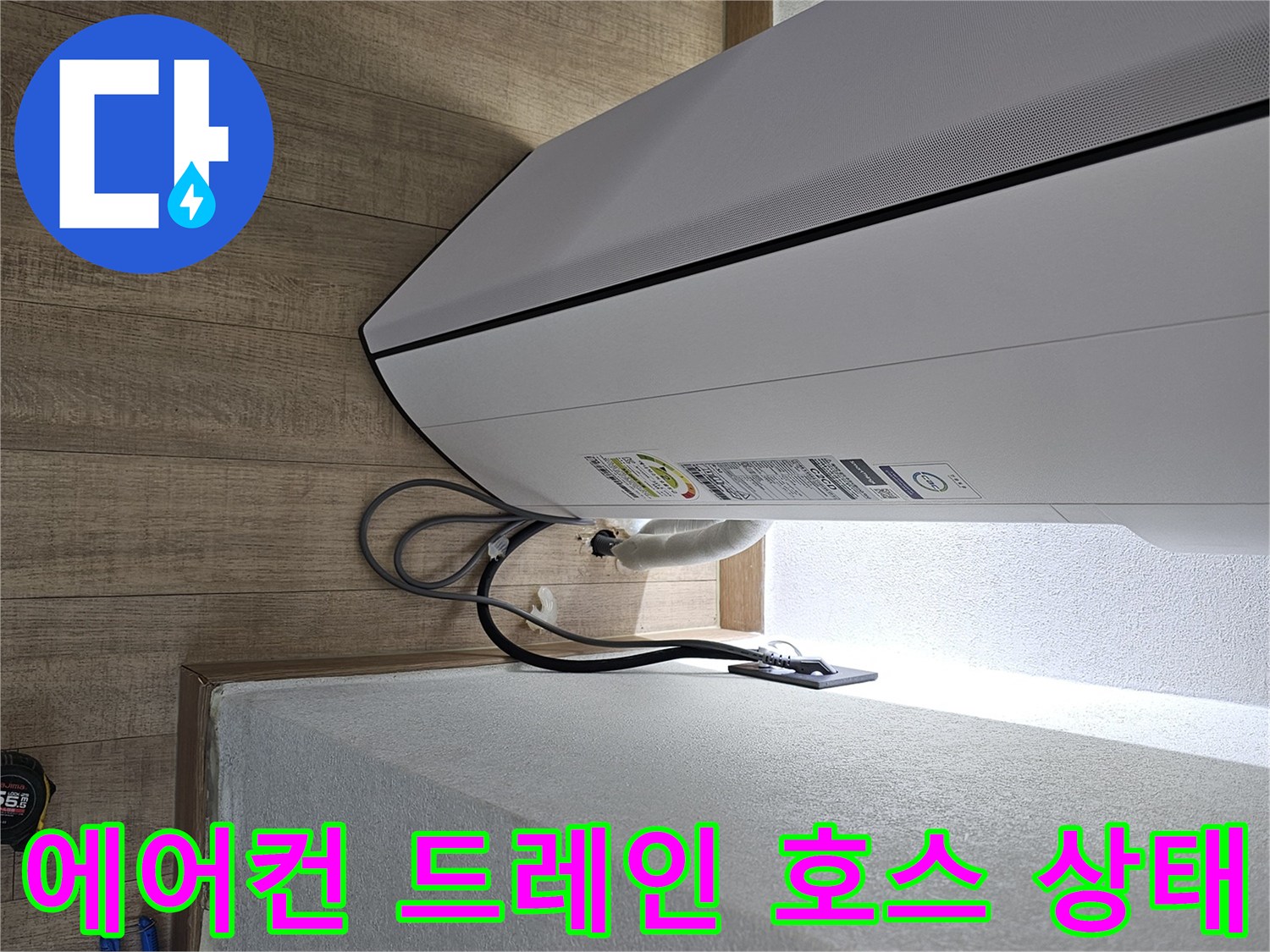 에어컨 본체 하단에서 나오는 드레인 호스의 연결 상태를 보여주는 사진