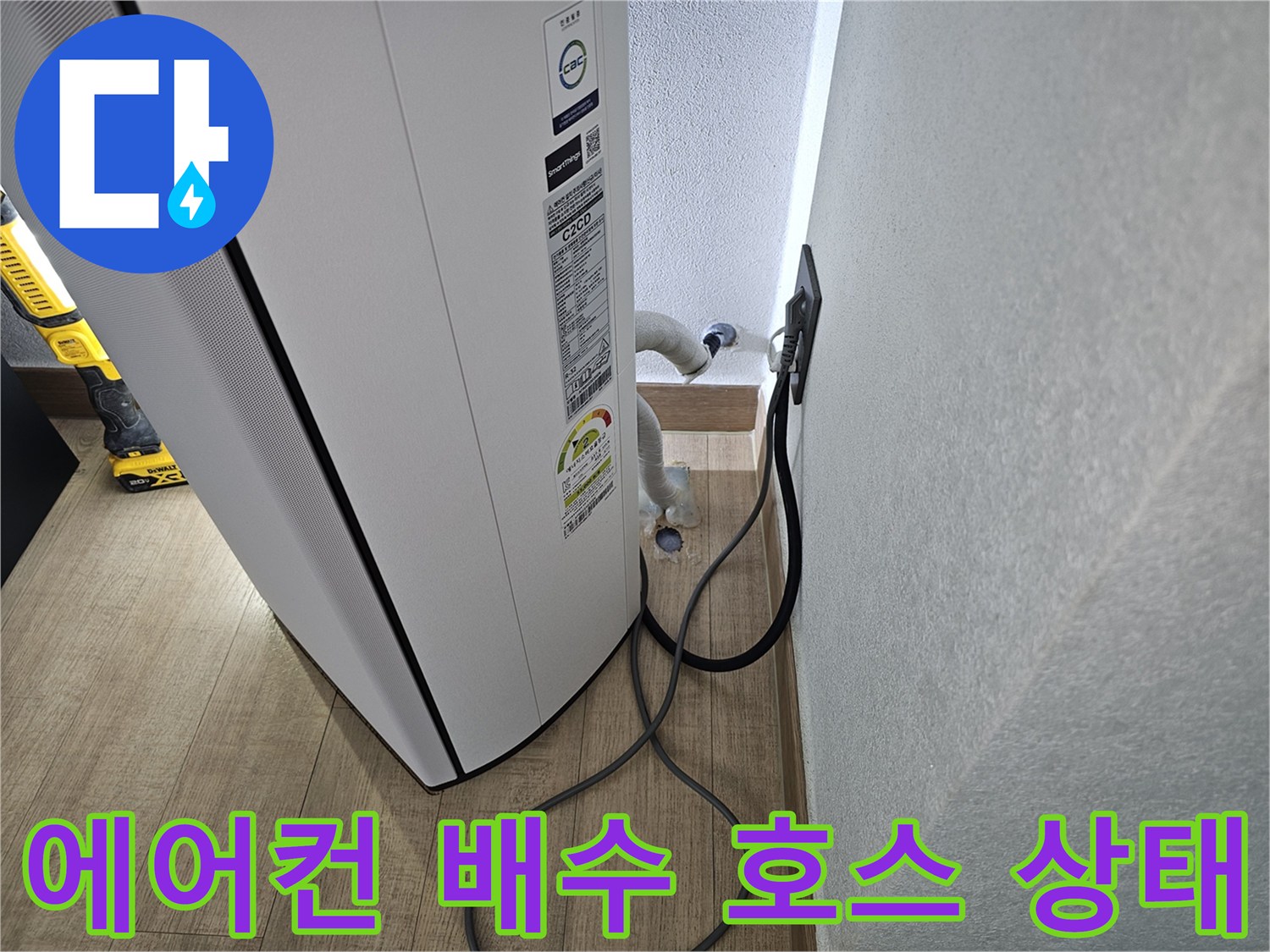 에어컨 본체 하단에서 연결된 드레인 호스의 배치 상태를 보여주는 사진입니다.