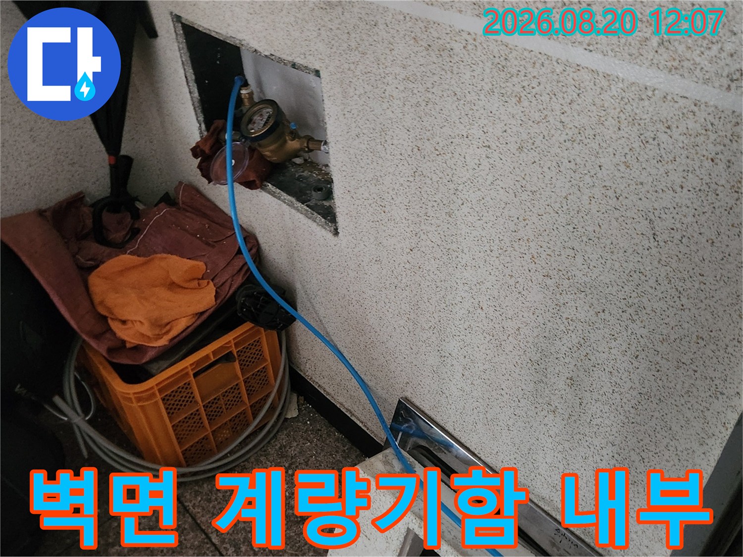 타일 벽면에 설치된 수도 계량기와 연결 호스