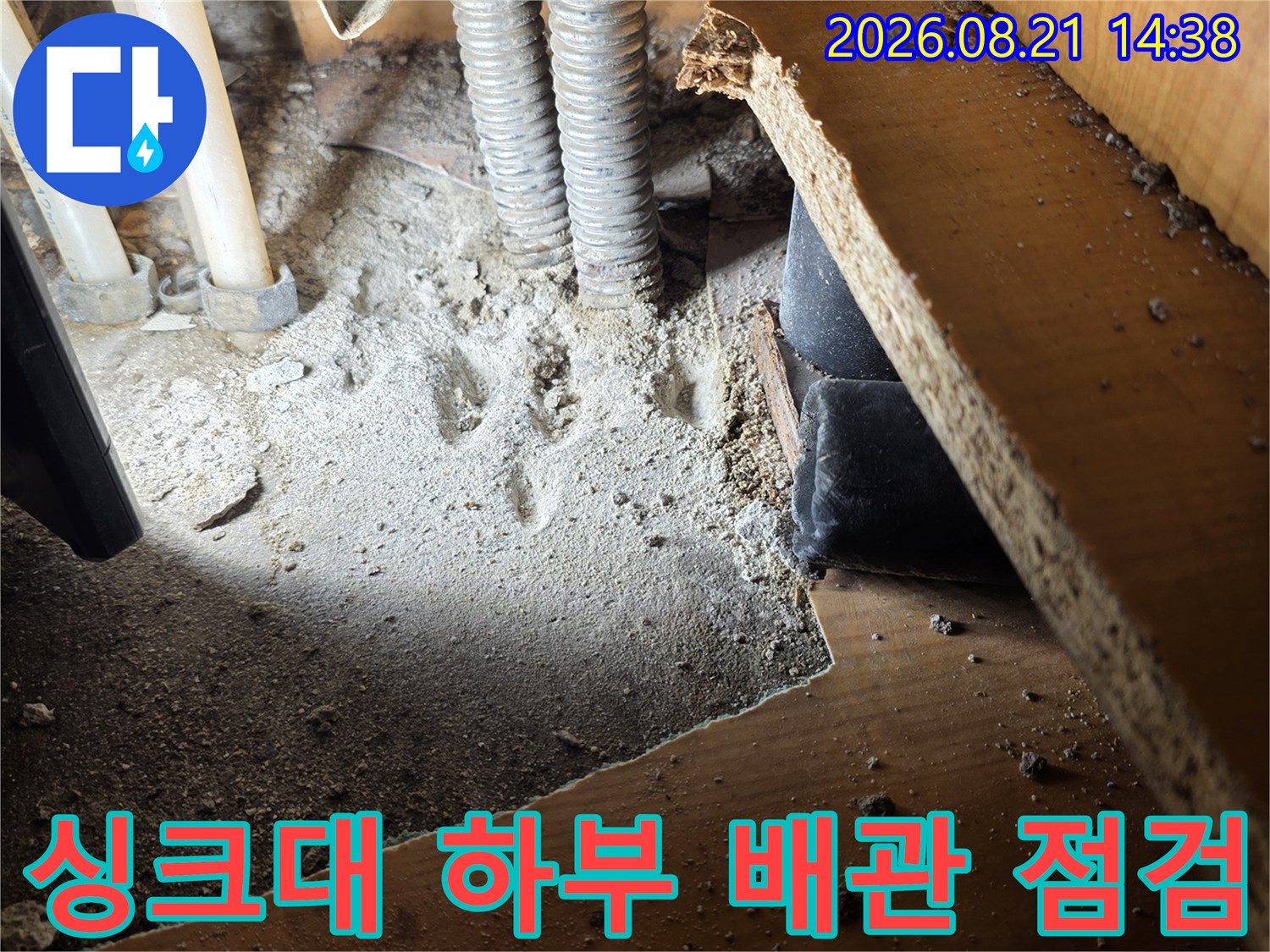 싱크대 하단에 위치한 주름관과 연결 배관의 상태를 확인하고 있습니다.