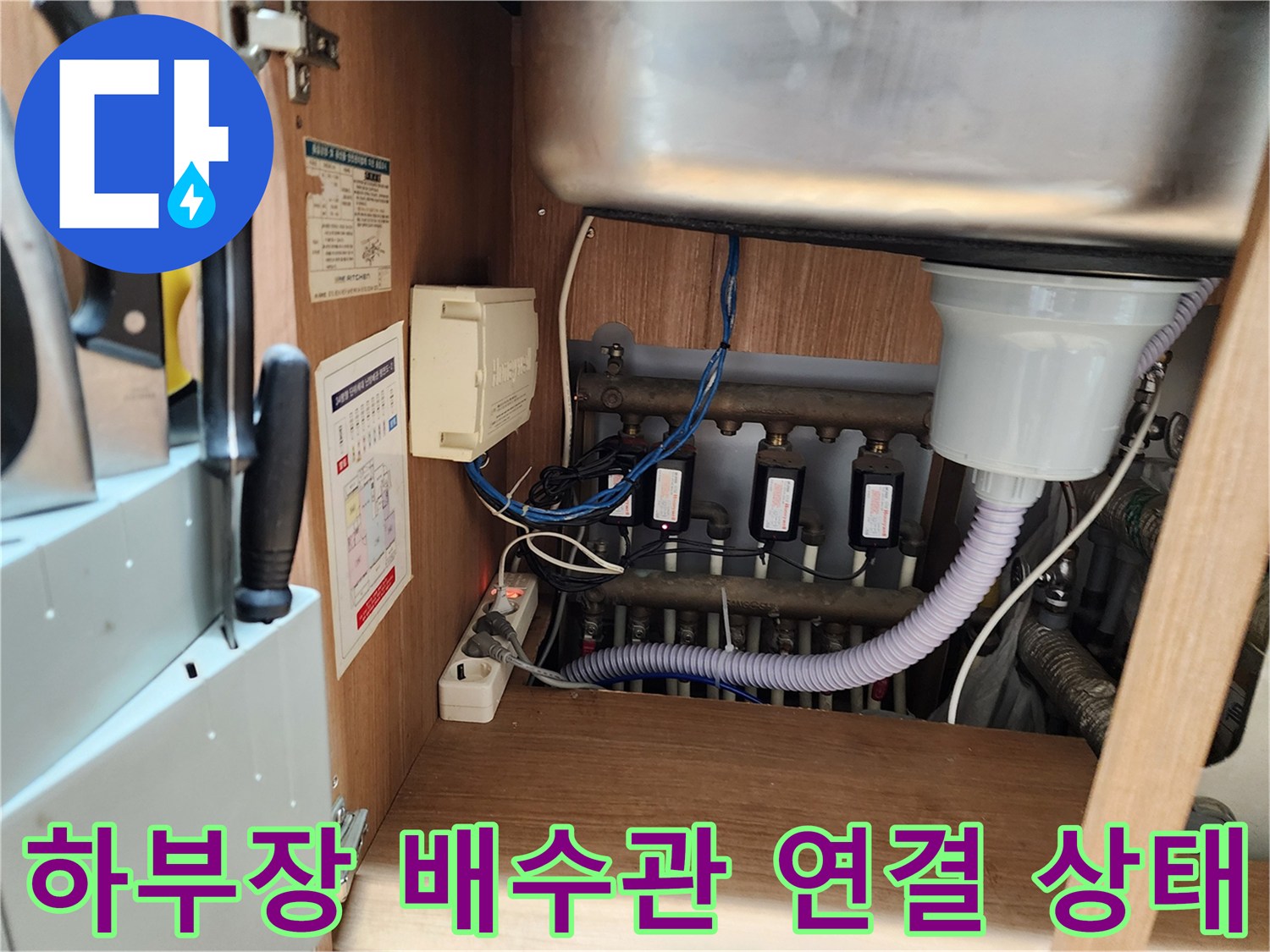 싱크대 아래쪽의 굵은 배관과 유연한 호스 연결 부위
