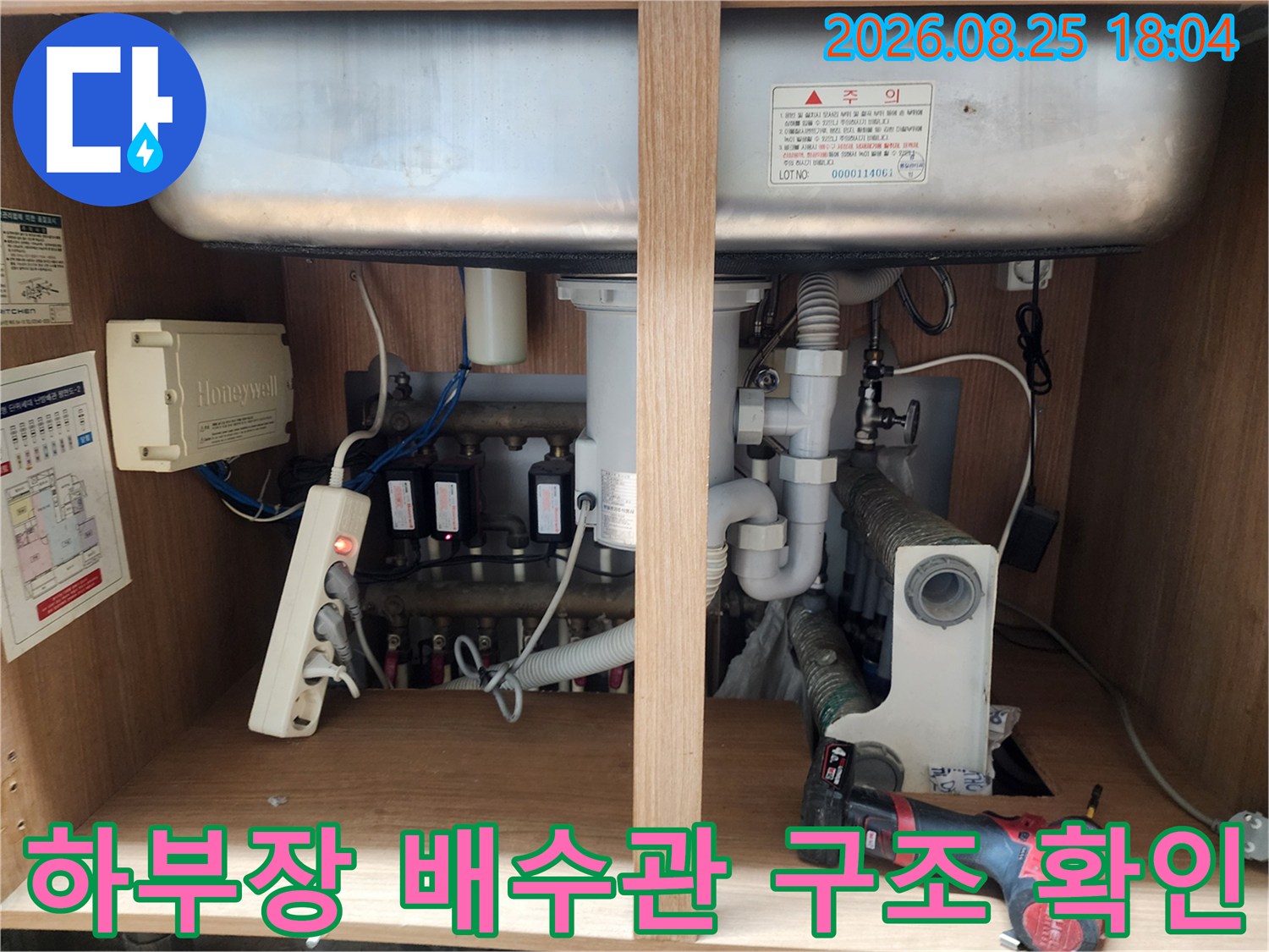 싱크대 하단 수납장 내부의 밸브와 호스 연결 부위를 상세히 촬영한 사진입니다.
