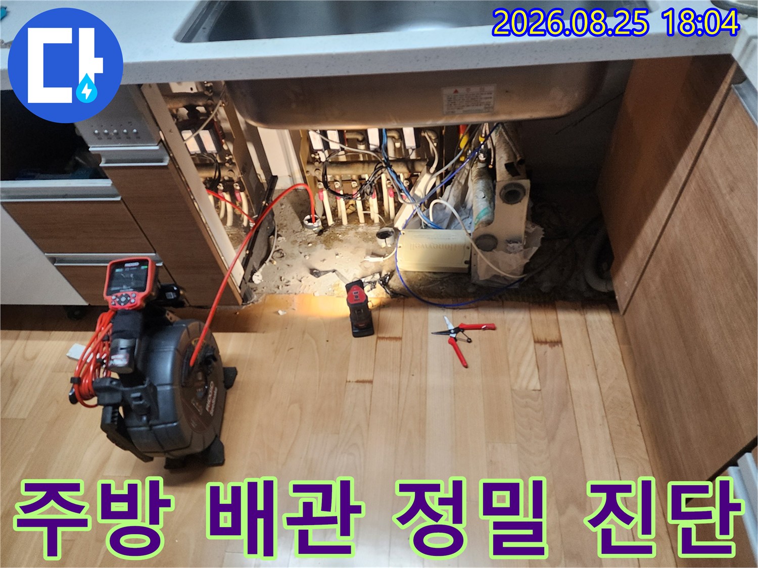 싱크대 하부 수납장을 열고 배관의 누수 지점을 찾기 위해 조사하는 모습입니다.