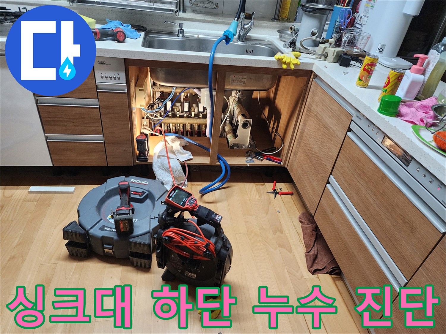 싱크대 하부장 내부의 노출된 배관과 작업용 전동 장비들
