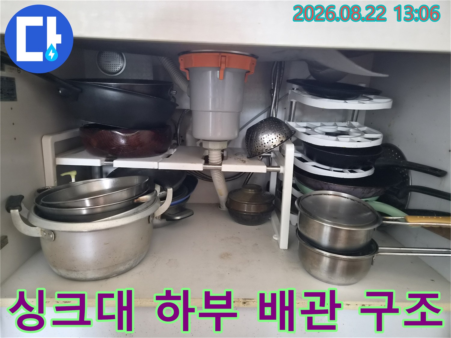 싱크대 밑 배수통-연결 호스와 주변 용기들