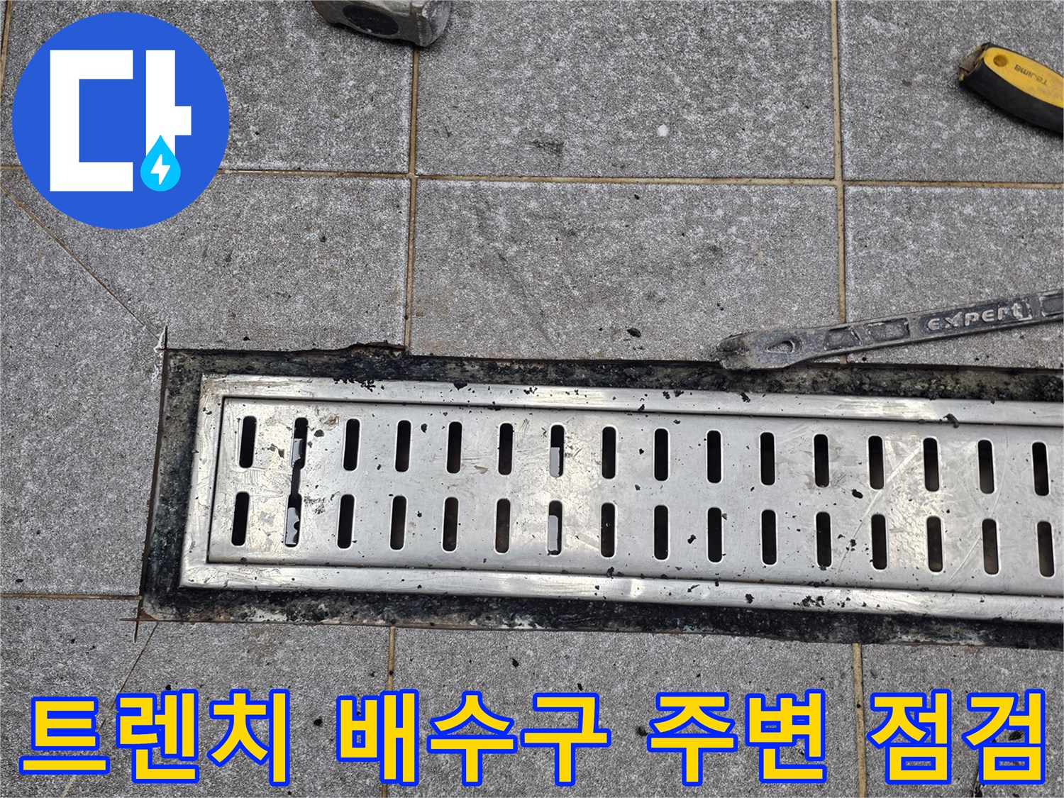 금속 트렌치 덮개와 주변 타일 상태를 확인하는 공사 현장
