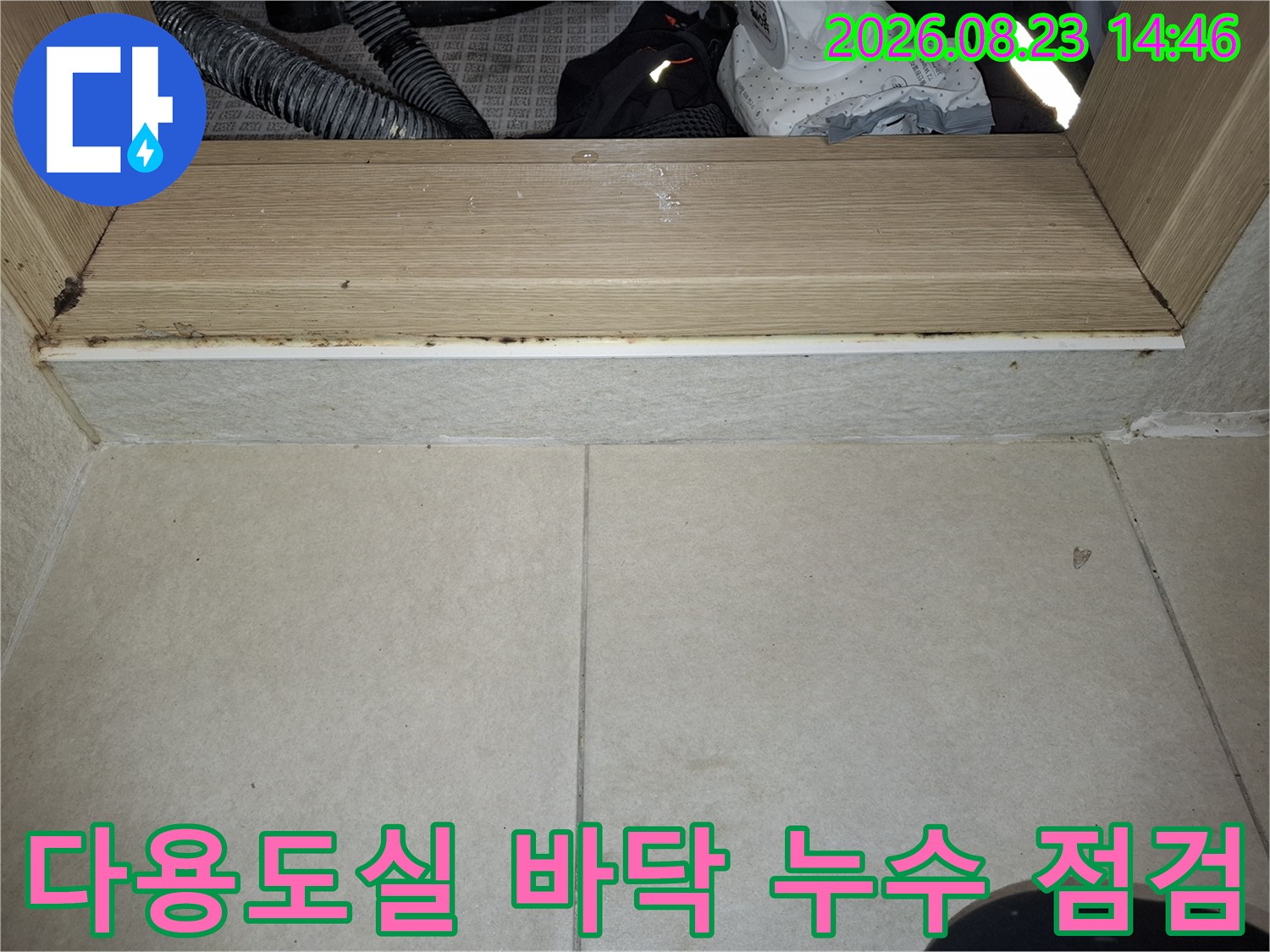 다용도실 배수구 주변의 타일과 프레임 사이 오염 상태를 촬영한 사진입니다.