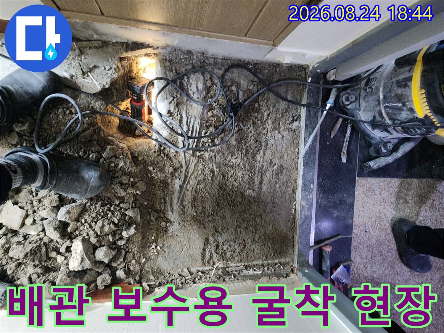 욕실 입구 쪽 바닥을 파헤쳐 배관의 상태를 점검하고 있는 작업 장면입니다.
