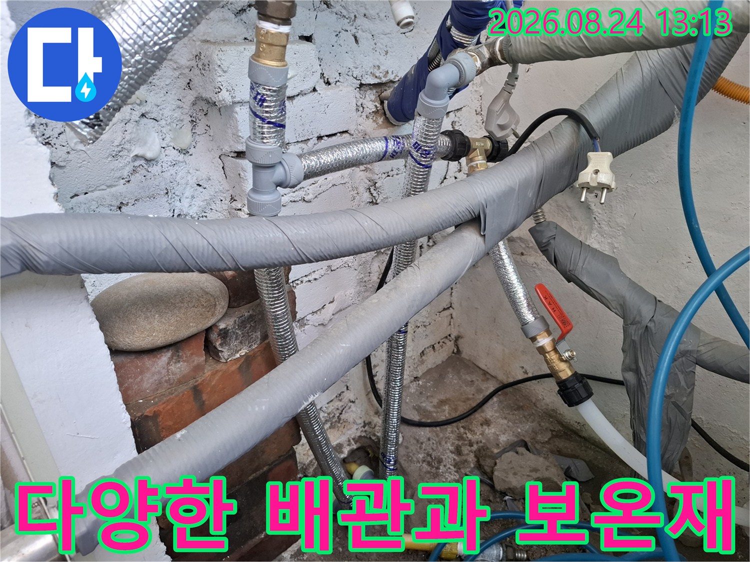 보일러실의 금속 밸브와 보온재로 감싸진 배관들이 복잡하게 연결되어 있습니다.
