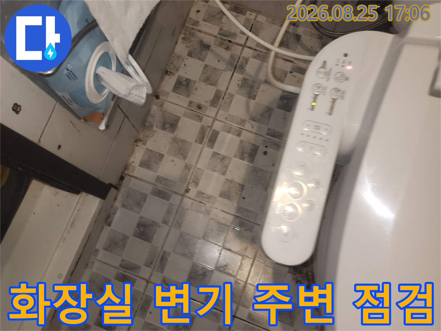 화장실 변기 하단의 타일 줄눈과 배관 연결 부위를 근접 촬영했습니다.