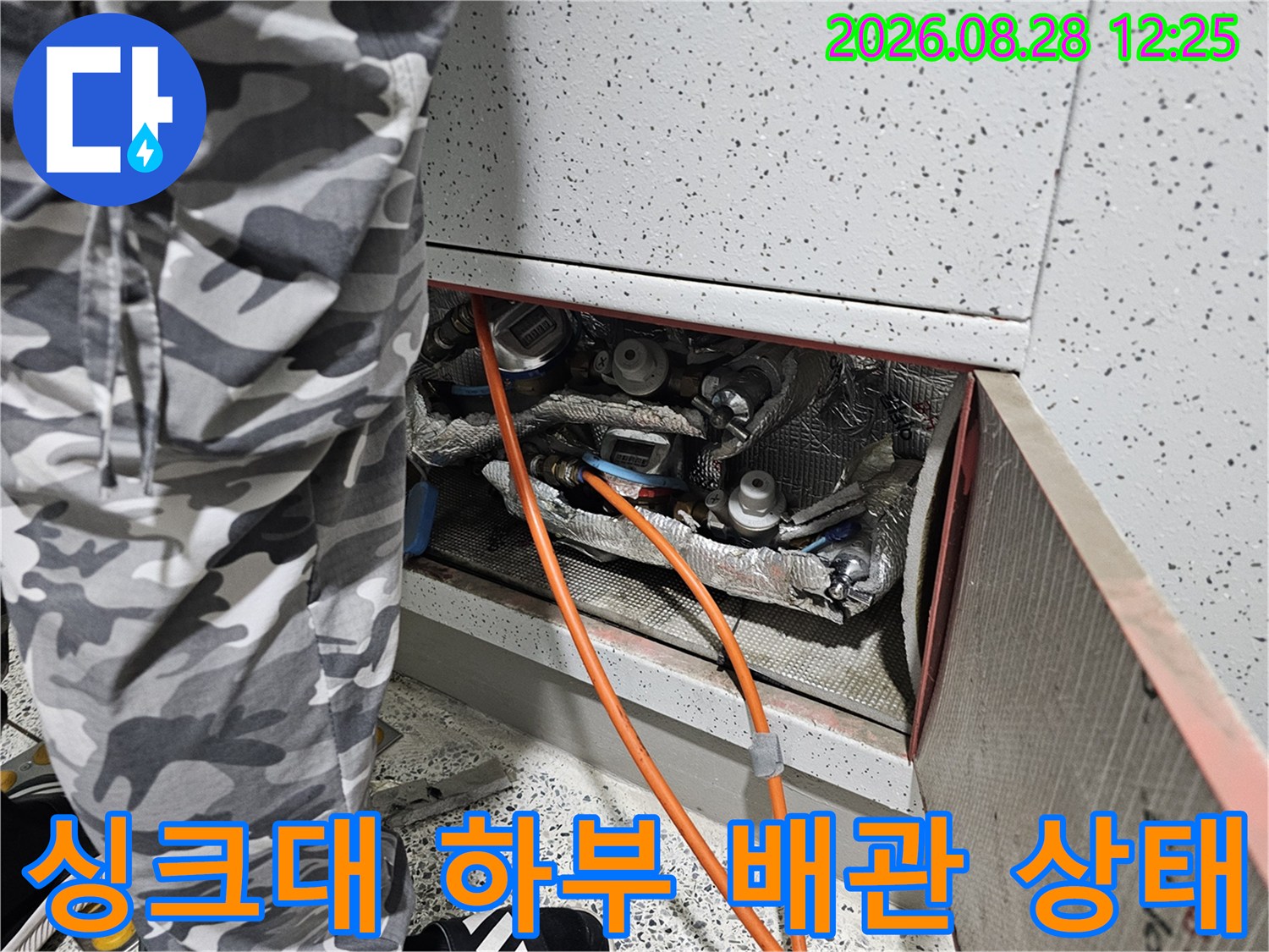 싱크대 하단 공간에 위치한 각종 배관과 연결 부위를 점검하는 장면입니다.