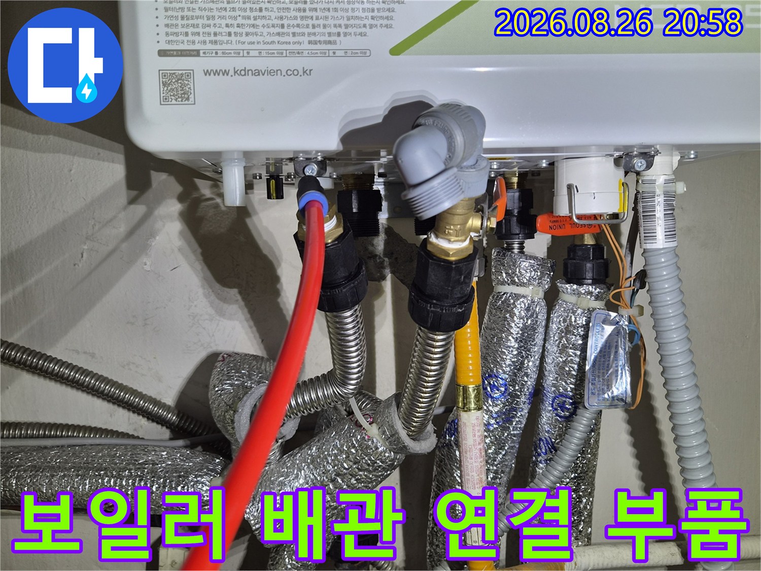 보일러 아래쪽 금속 부품과 은박 보온재로 마감된 배관의 근접 사진입니다.