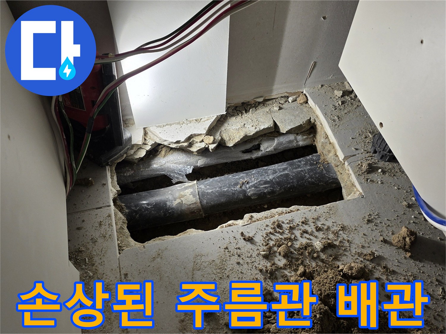 싱크대 아래 젖은 흙 속에 노출된 파손된 검은색 배관