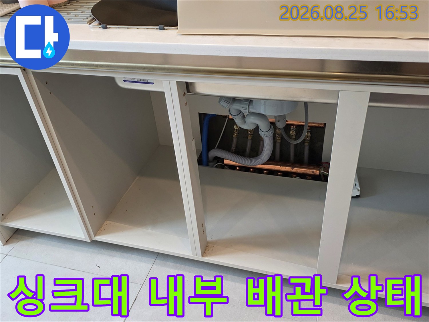 싱크대 하부장-내부에 노출된 배수 호스와 관로의 연결 상태를 촬영한 사진입니다.