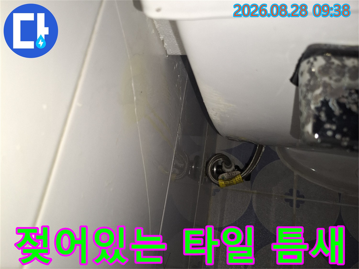변기 부속품 주변의 젖은 타일 틈새를 촬영한 사진입니다.