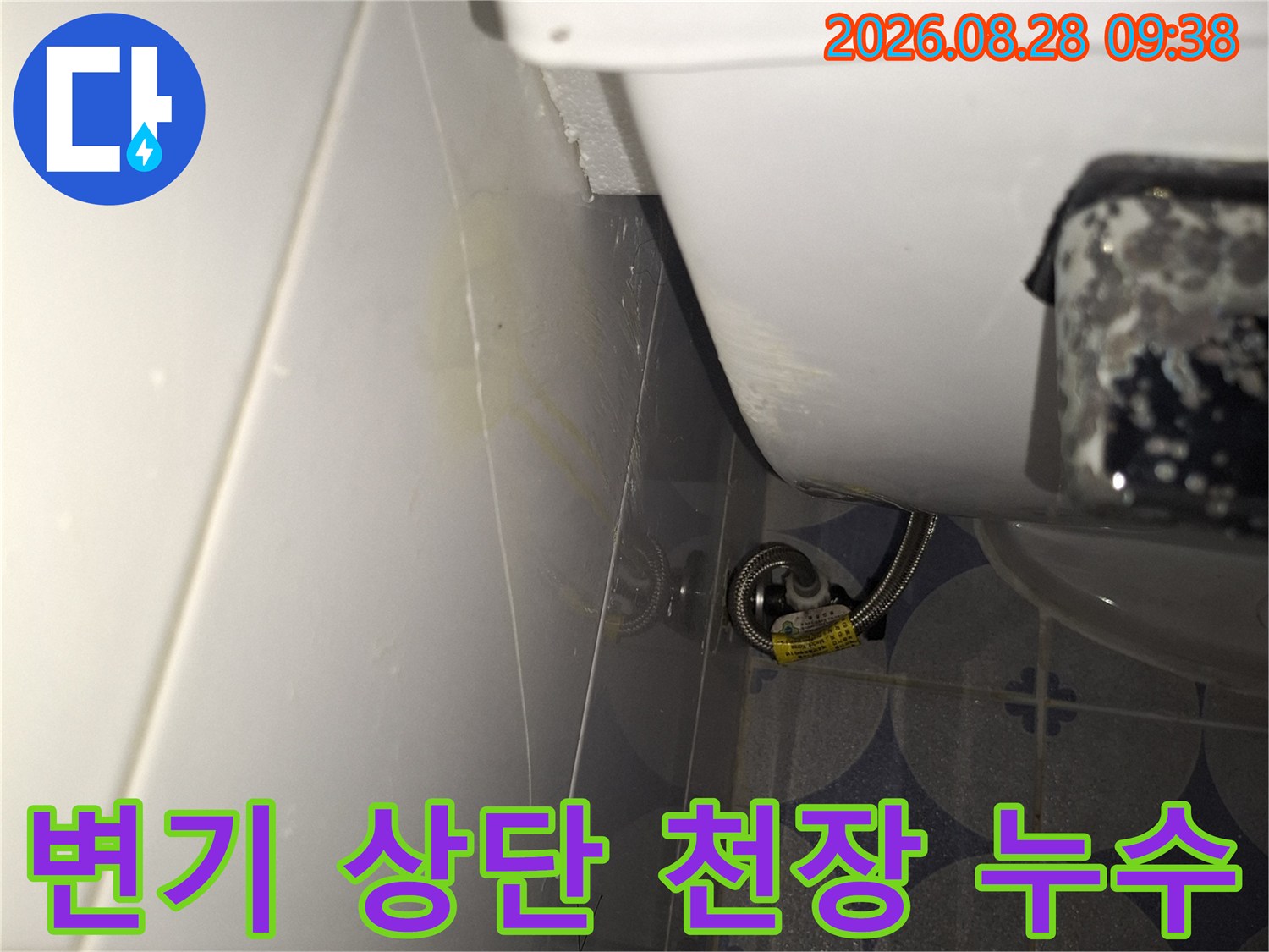 변기 탱크 위쪽 천장 타일 부분에 나타난 누수 흔적과 습기 상태입니다.