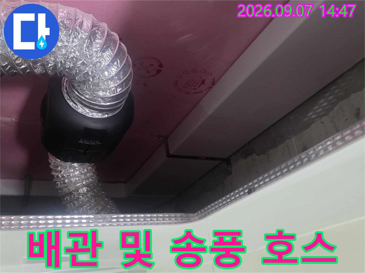 분홍색 천장재와 연결된 투명한 배관 호스 및 검은색 부품