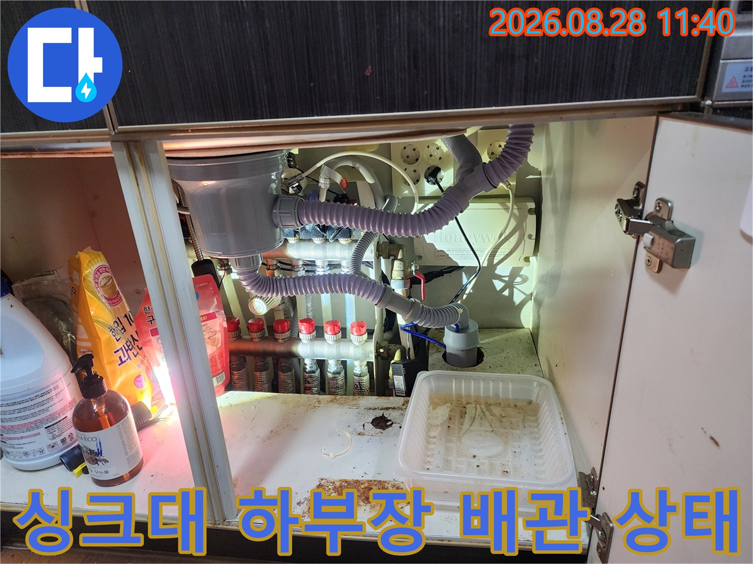 남양주 진접읍 주방 싱크대 아래쪽의 복잡한 정수기 및 에어컨 드레인 배관 연결 부위 모습입니다.