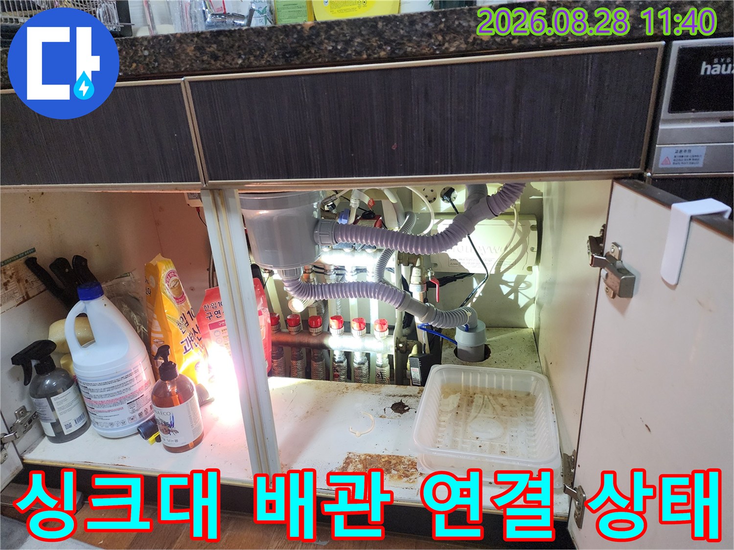 싱크대 하단 내부의 복잡한 드레인 호스와 배수 배관 모습