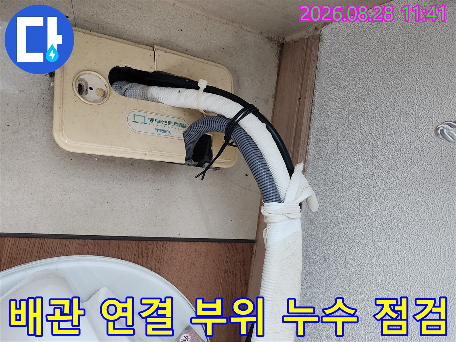 하얀색 배관 마감재와 드레인 호스가 만나는 지점의 상세 사진입니다.