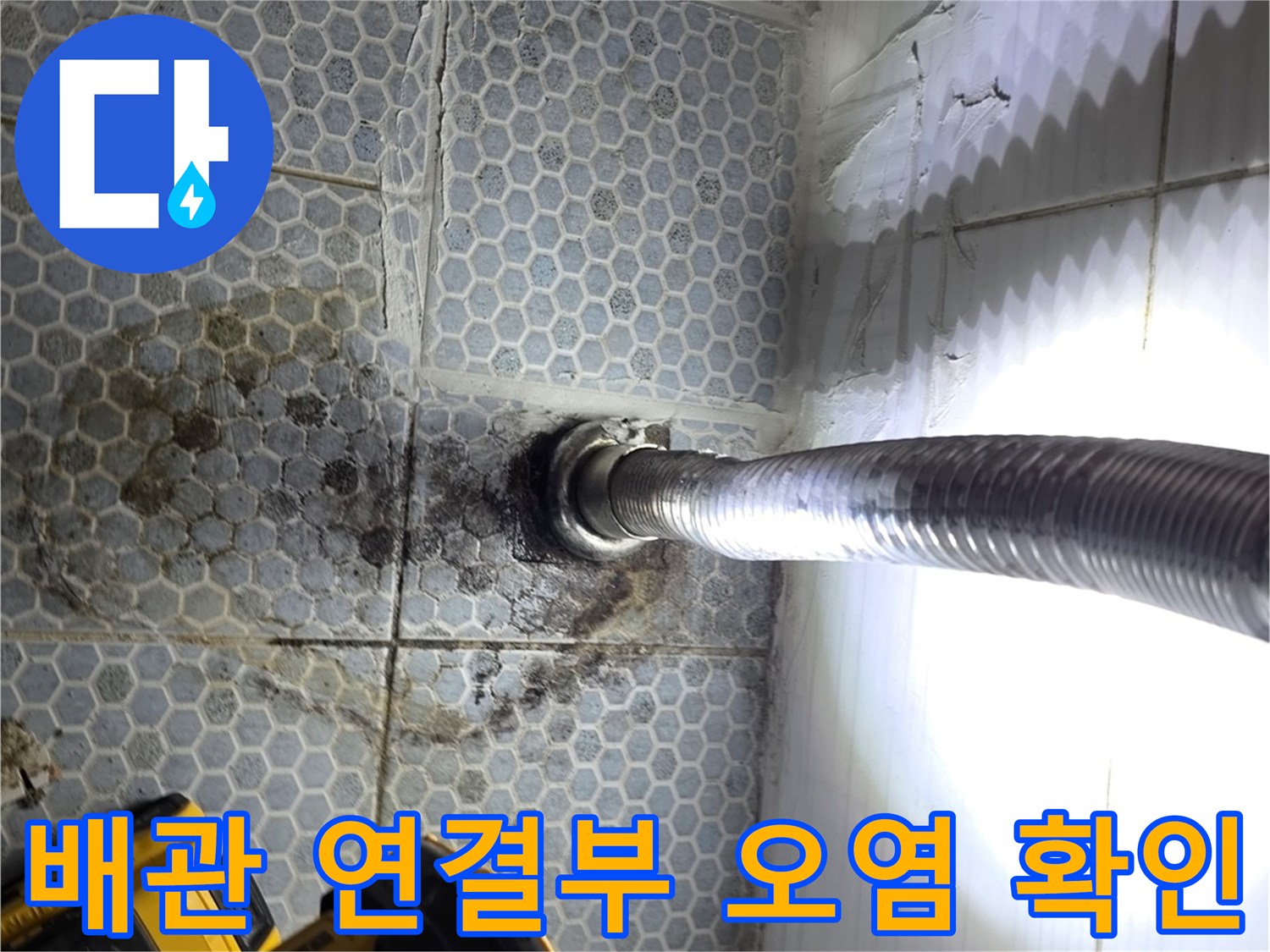 배관 주변 타일의 짙은 얼룩과 은색 배관 자바라 모습