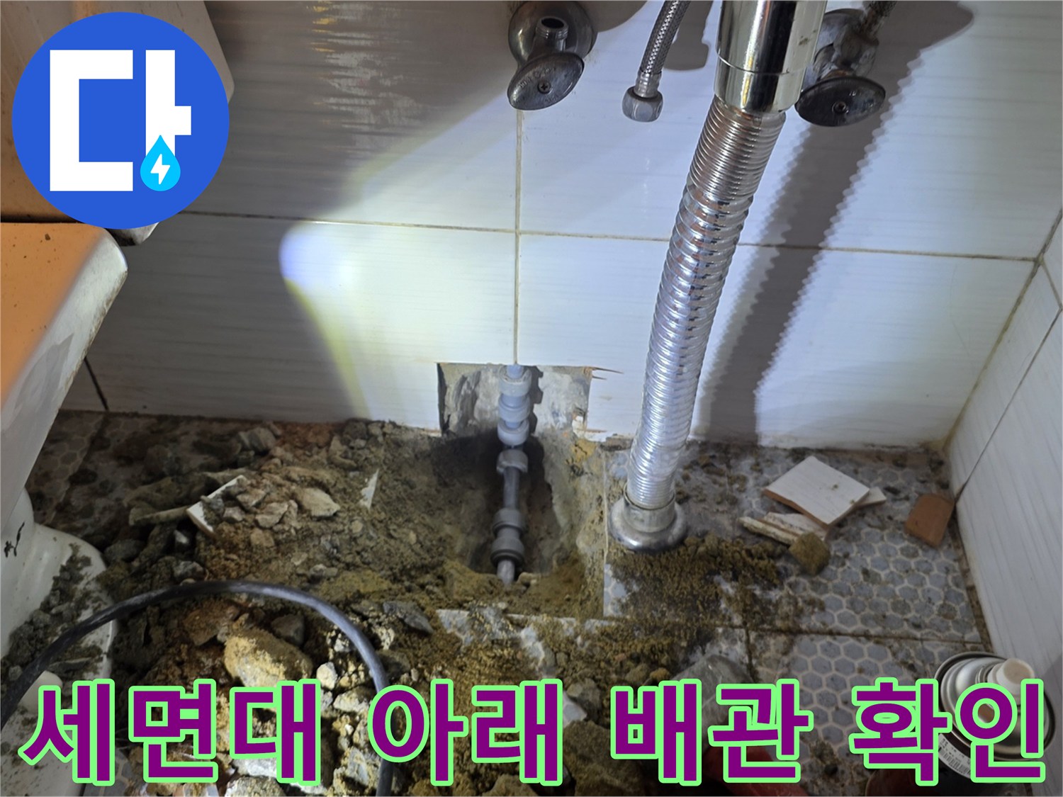 세면대 하단부 굴착을 통해 드러난 노출된 매립 배관과 공구들