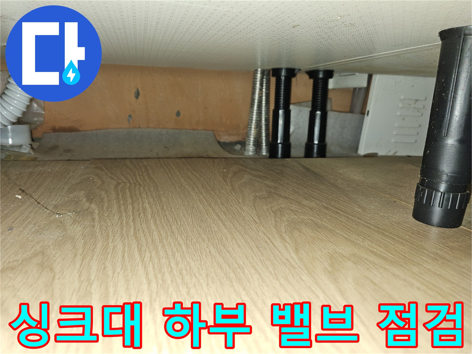 싱크대 아래쪽 검은색 밸브와 보온재 처리된 배관의 연결 부위 촬영