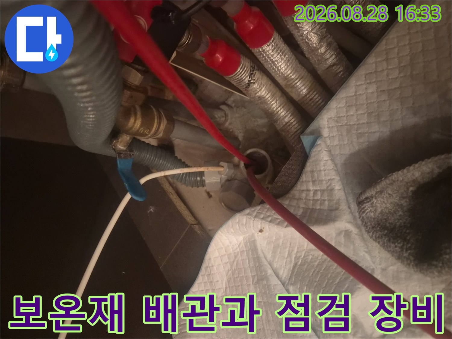 은색 보온재가 감겨 있는 배관들과 작업용 빨간 케이블의 모습