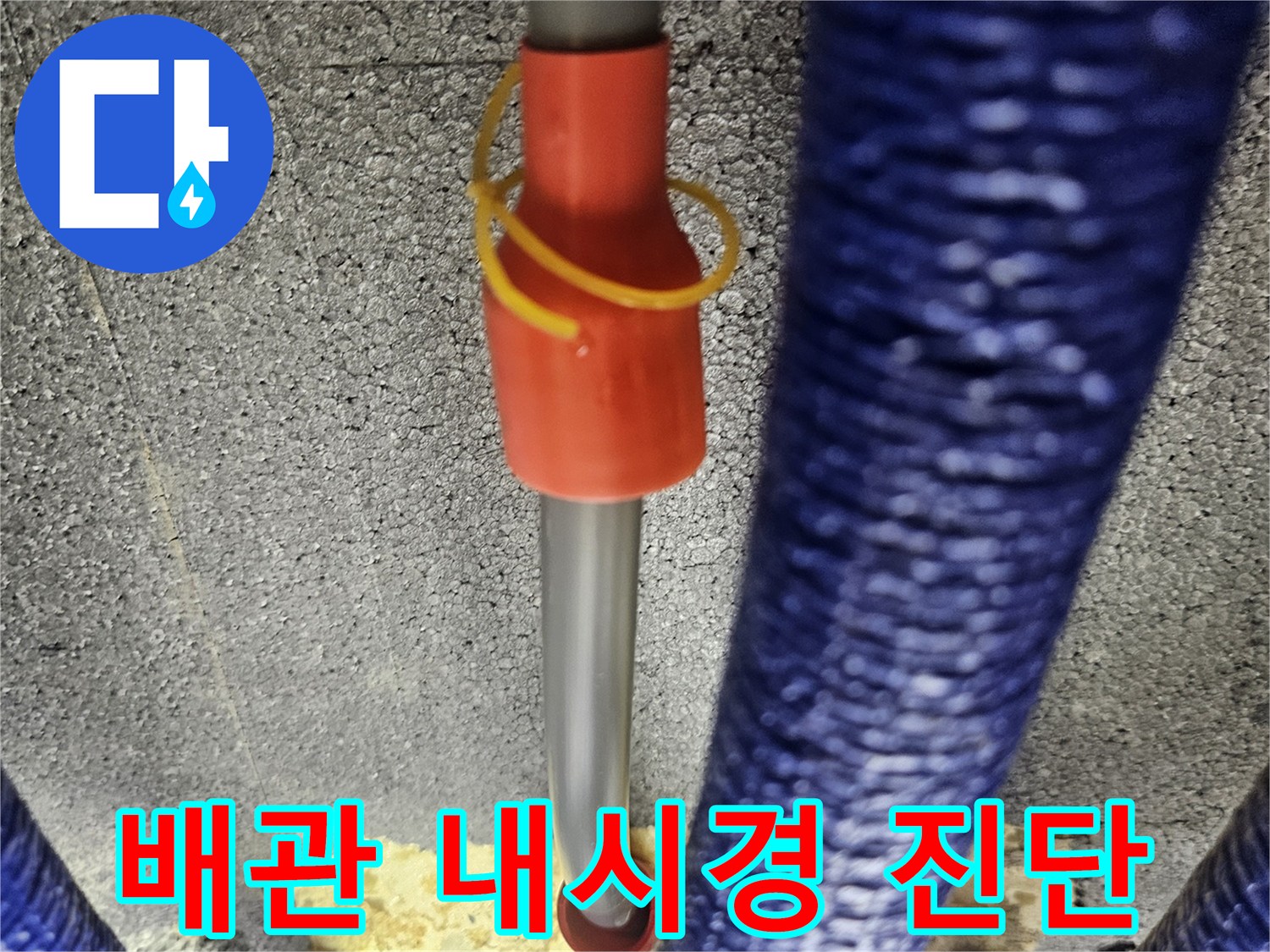파란색 보온재가 감겨있는 배관 사이로 내시경 카메라를 투입하여 점검하는 모습