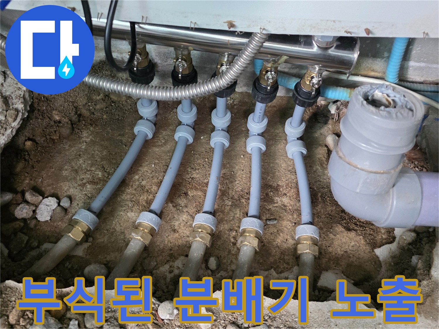 싱크대 아래 굴착 부위-부식된 금속 배관과 자갈 토사