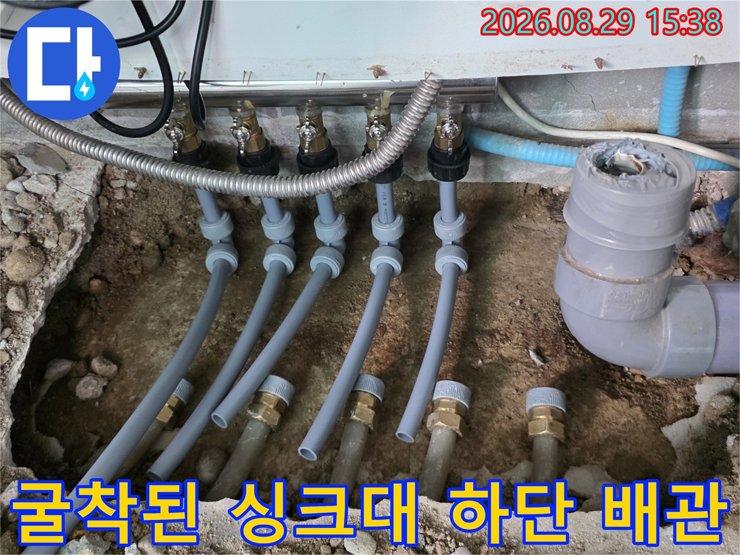 싱크대 아래 노출된 분배기 밸브와 여러 배관들