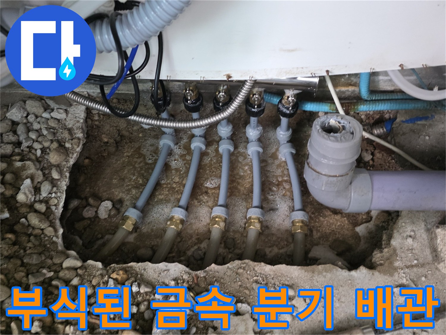 싱크대 하부 흙과 자갈 사이로 보이는 부식된 배관 연결부