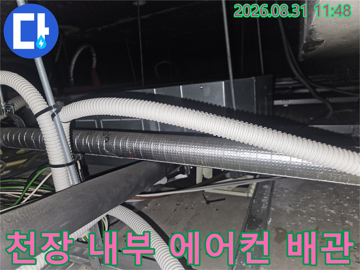 에어컨 드레인 시스템-은색 보온재와 흰색 호스가 연결된 천장 안쪽 모습입니다.