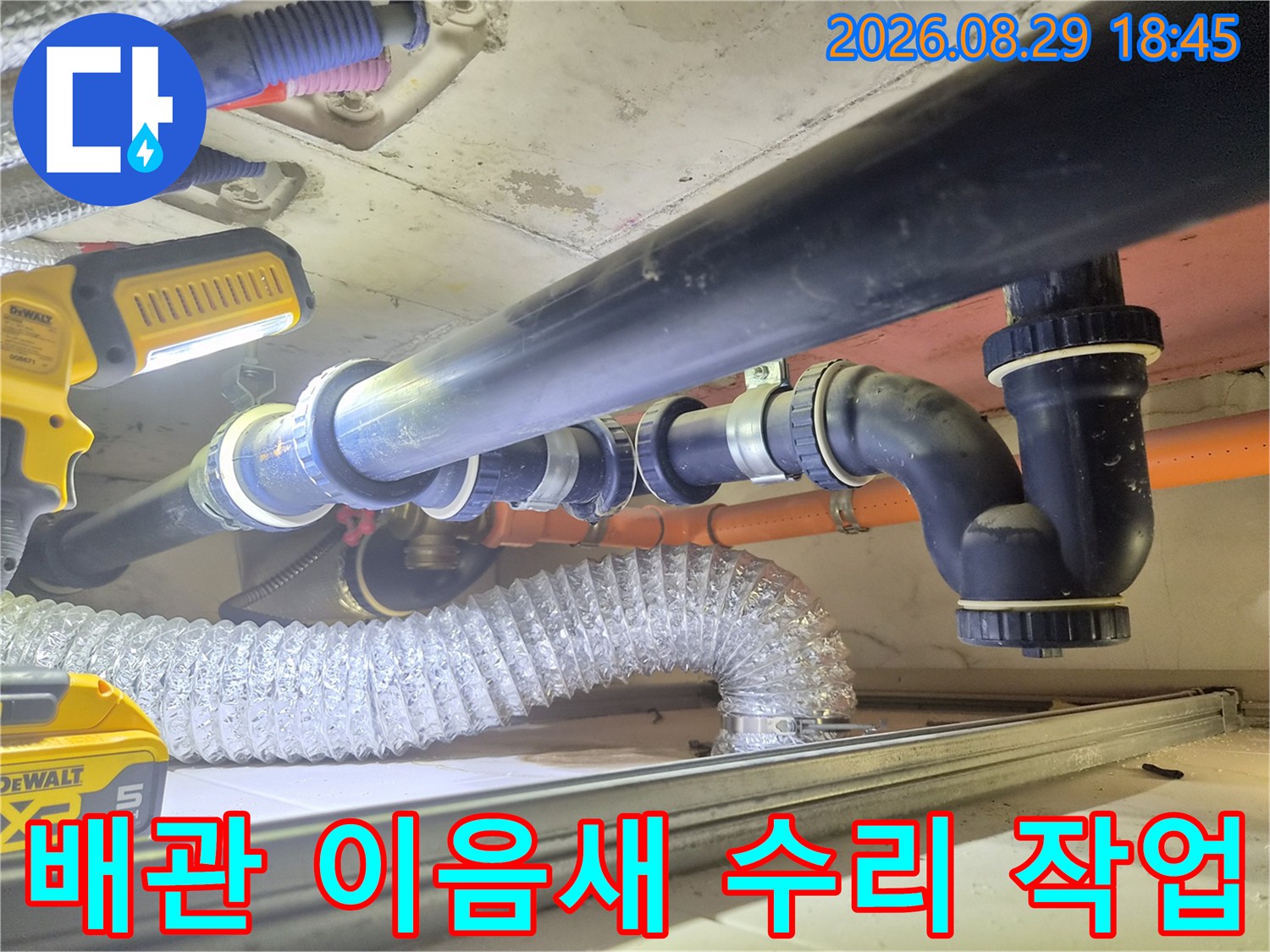 천장 내부의 검은색 배관과 연결된 부속품을 교체하고 있는 설비 공사 장면
