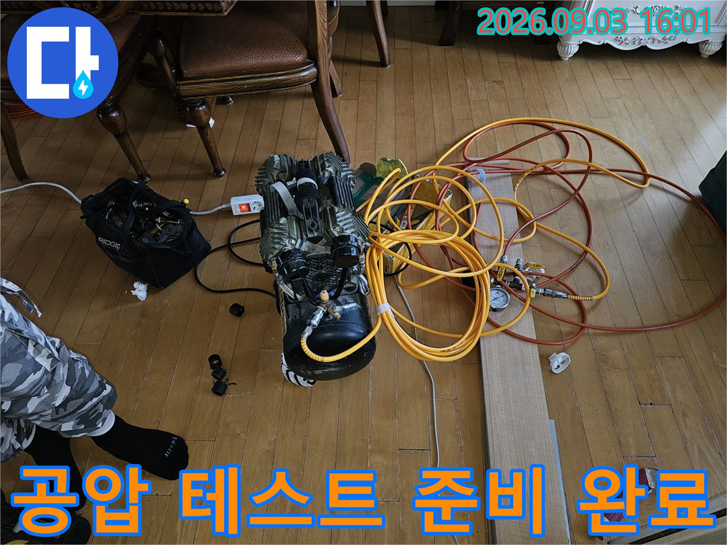 배관의 기밀성을 검사하기 위해 바닥에 펼쳐진 에어 호스와 콤프레샤