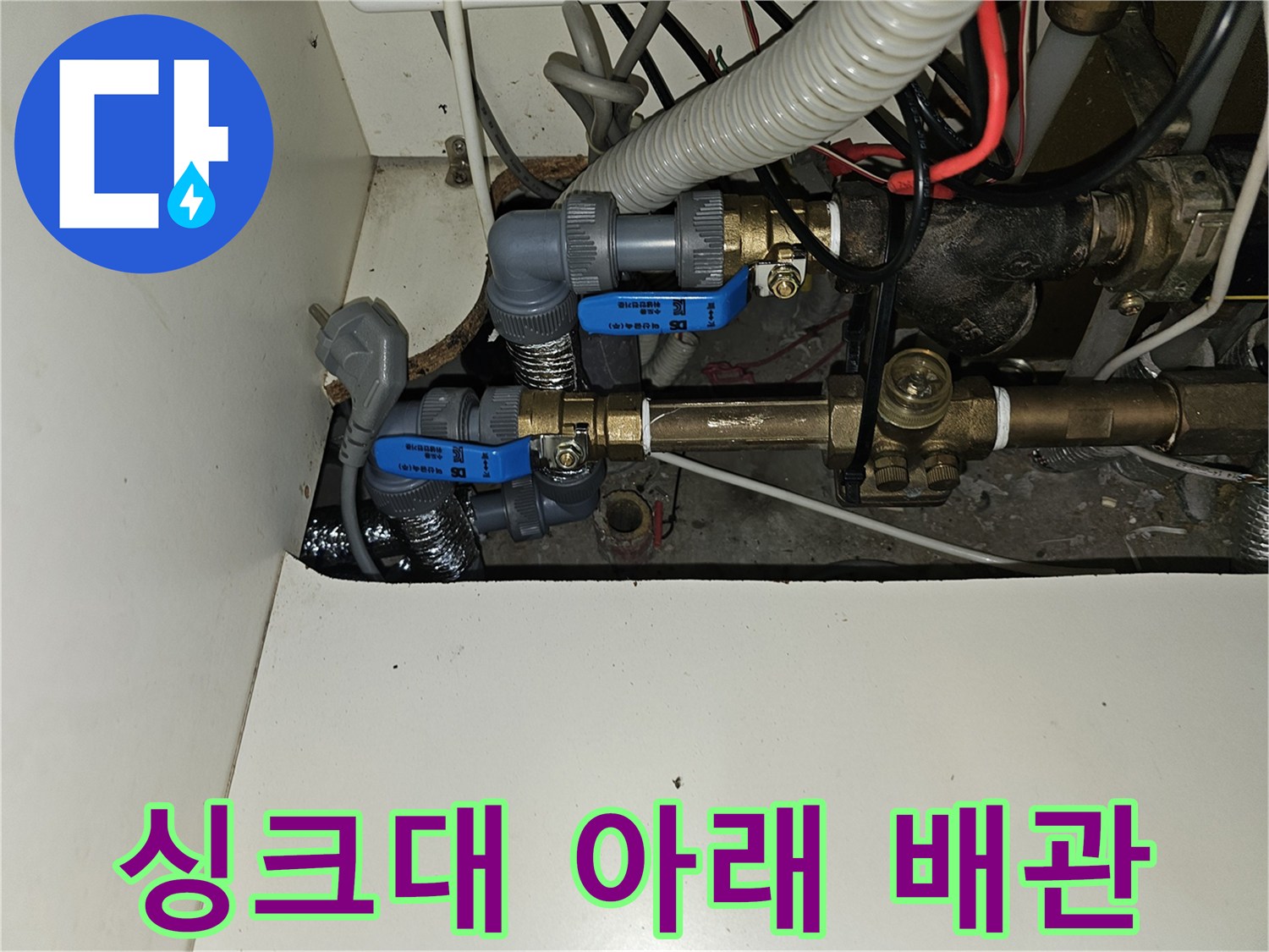 주방 하부장 내부에 노출된 난방용 금속 배관과 보온재 마감 부위