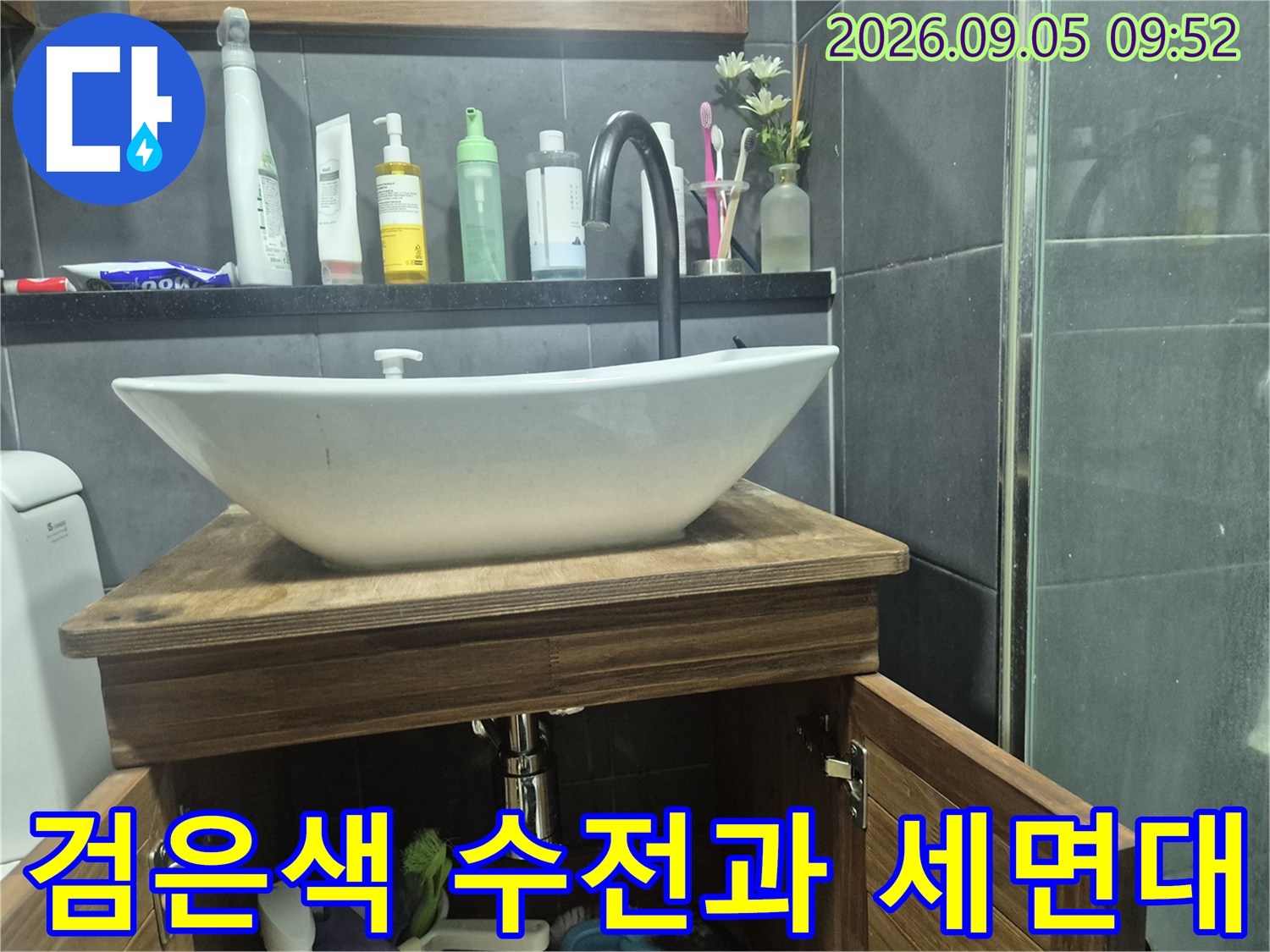 세면대 위 검은색 수전과 아래쪽 배관 연결 부위 근접 사진입니다.